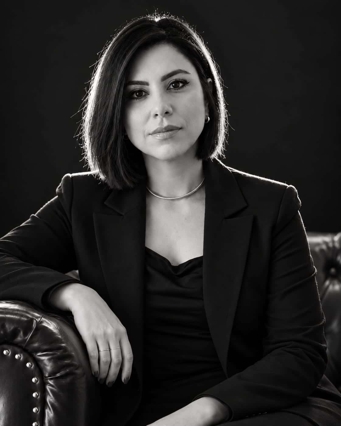 Simone Tatiana da Silva, advogada, em retrato em preto e branco, sentada em um sofá de couro